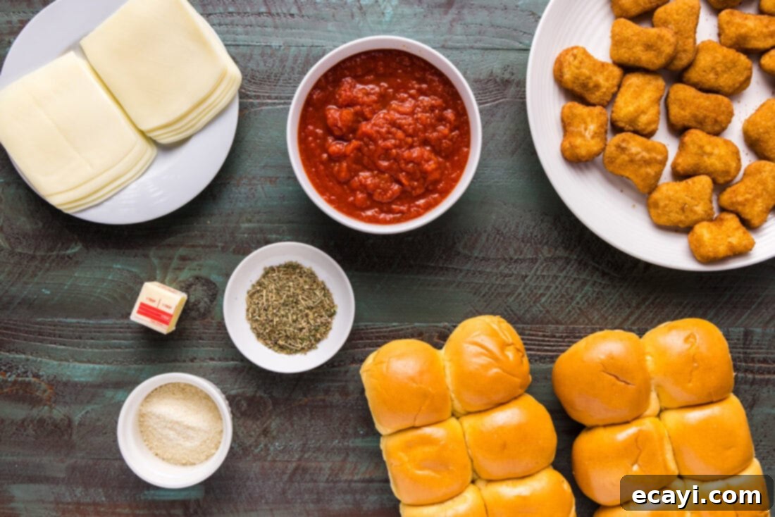 Cheesy Chicken Parmesan Sliders 4 A flat lay image displaying all the ingredients for Chicken Parmesan Sliders: slider buns, chicken nuggets, various cheeses, and marinara sauce