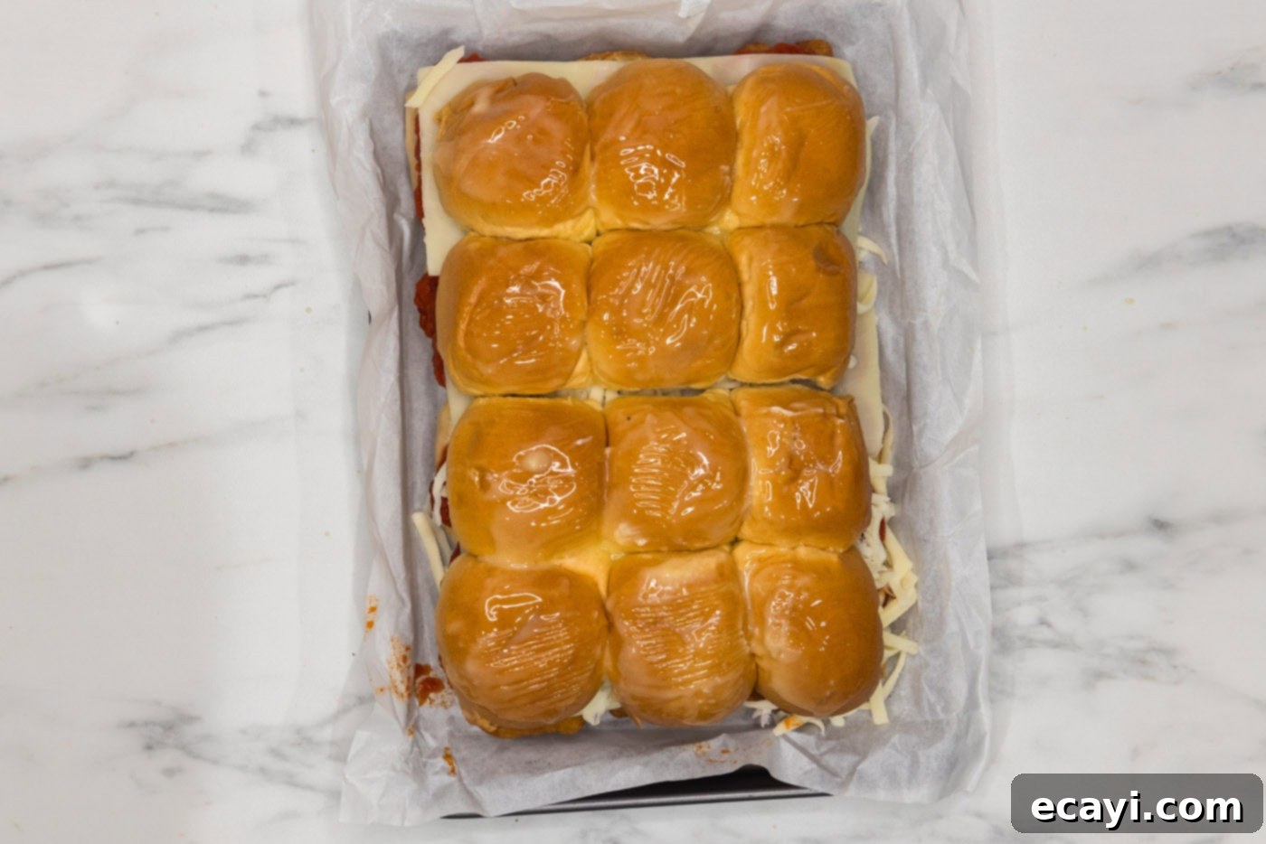 Cheesy Chicken Parmesan Sliders 10 Chicken parmesan sliders with top buns brushed with melted butter in a baking dish