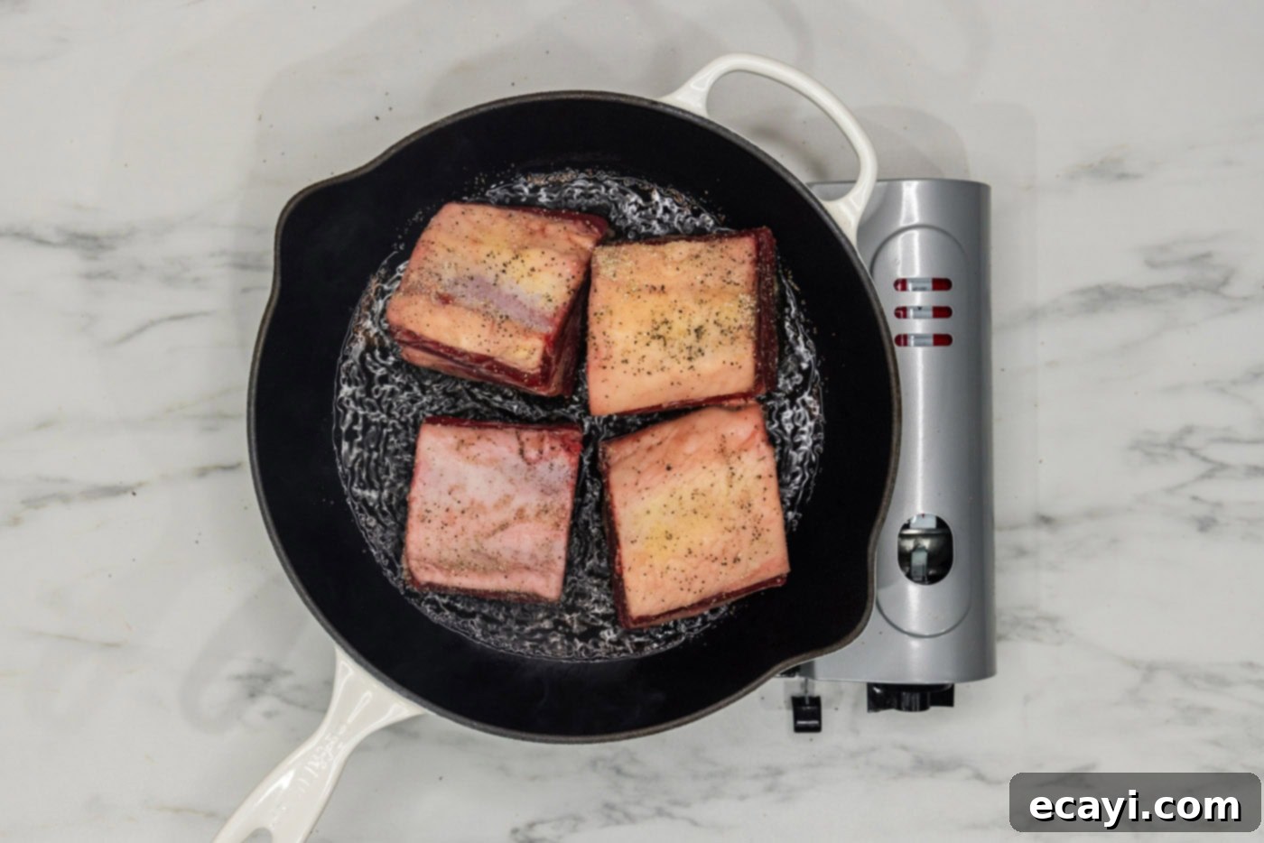 Rich & Tender Slow Cooker Short Ribs 5 short ribs searing in a skillet