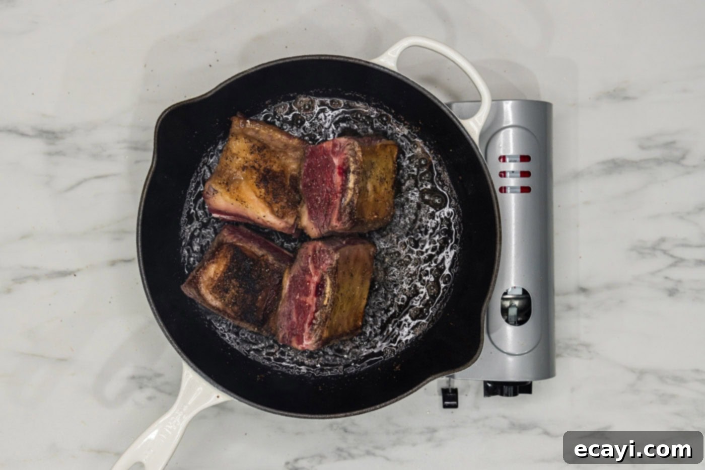 Rich & Tender Slow Cooker Short Ribs 6 beef short ribs searing in a skillet of oil