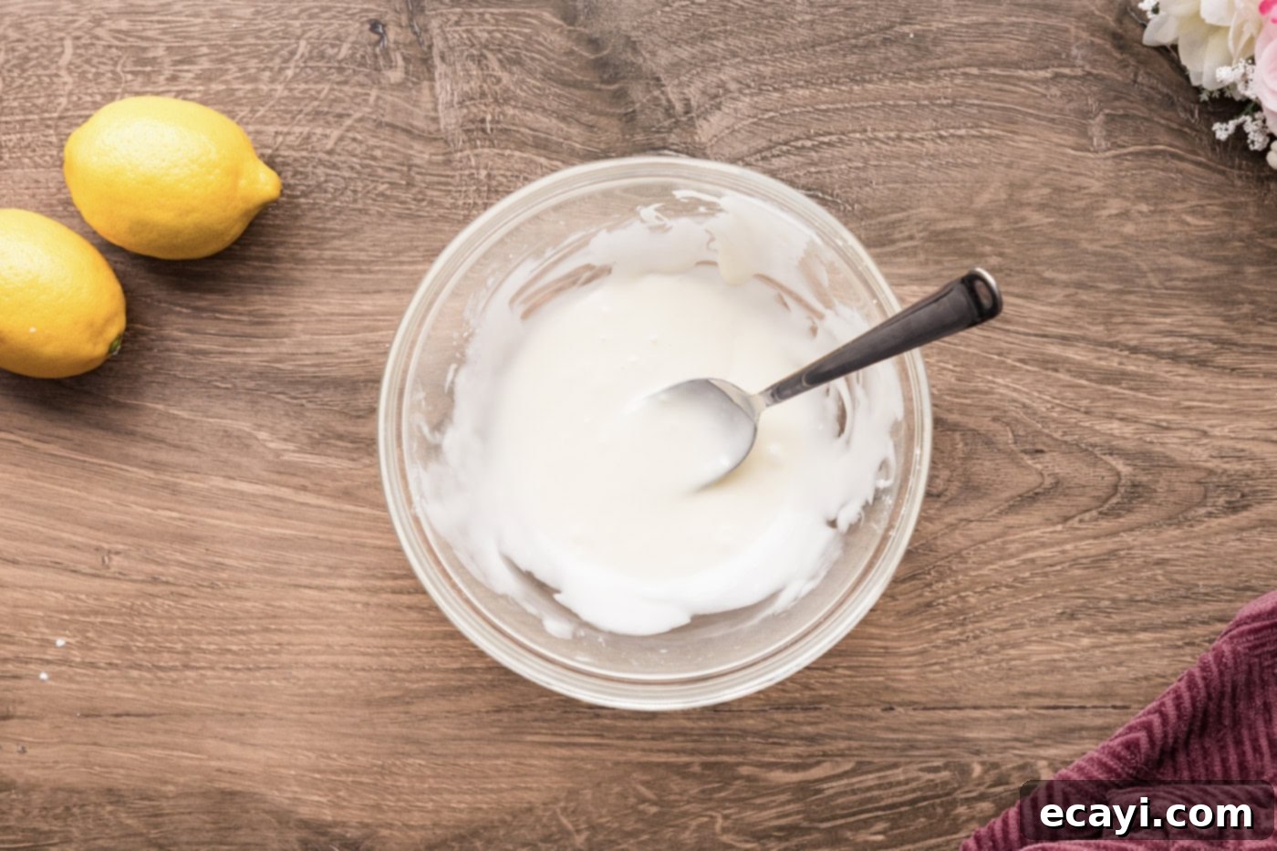 Zesty Lemon Crumble Bars 11 Mixed lemon icing in a small bowl with a spoon, showing its thick drizzling consistency.