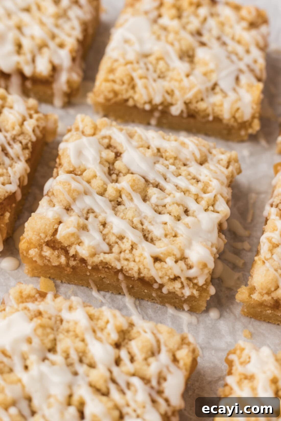 Zesty Lemon Crumble Bars 3 Close up photo of Lemon Streusel Squares on parchment paper, showing the golden-brown edges and the vibrant lemon curd layer underneath the streusel.