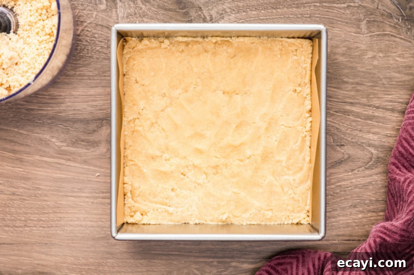 Zesty Lemon Crumble Bars 7 Crumb mixture pressed evenly into a 9x9 inch pan, forming the base layer for the lemon streusel squares.
