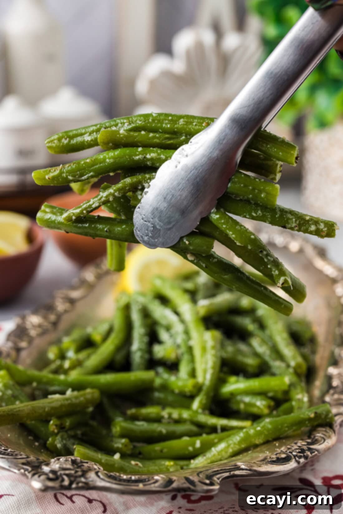 Perfect Instant Pot Green Beans 2 Tongs holding up a bunch of vibrant Instant Pot Green Beans seasoned with butter