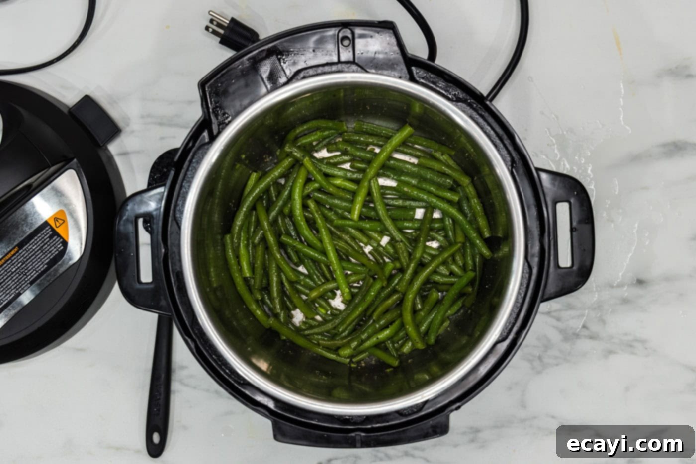 Perfect Instant Pot Green Beans 7 Steamed green beans being tossed with melted butter and seasonings in the Instant Pot