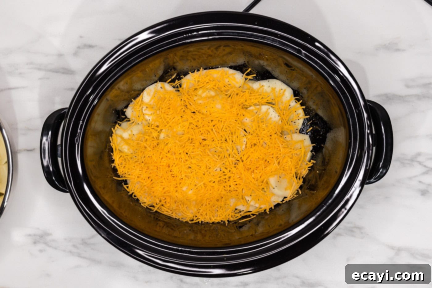 Set It and Forget It Scalloped Potatoes 11 layer of cheddar cheese over sliced potatoes in a crockpot