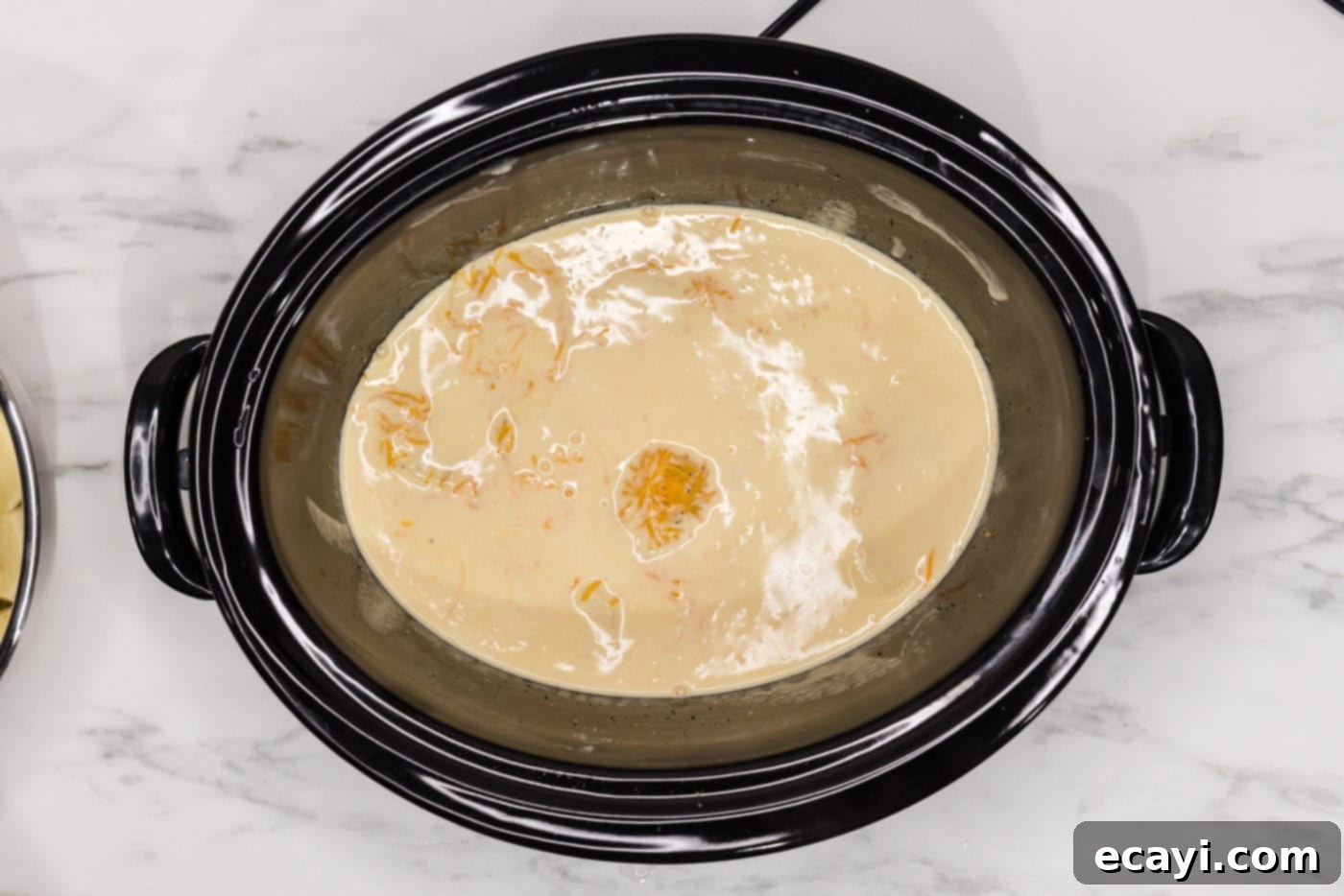 Set It and Forget It Scalloped Potatoes 12 cheese sauce on top of sliced potatoes in a crockpot
