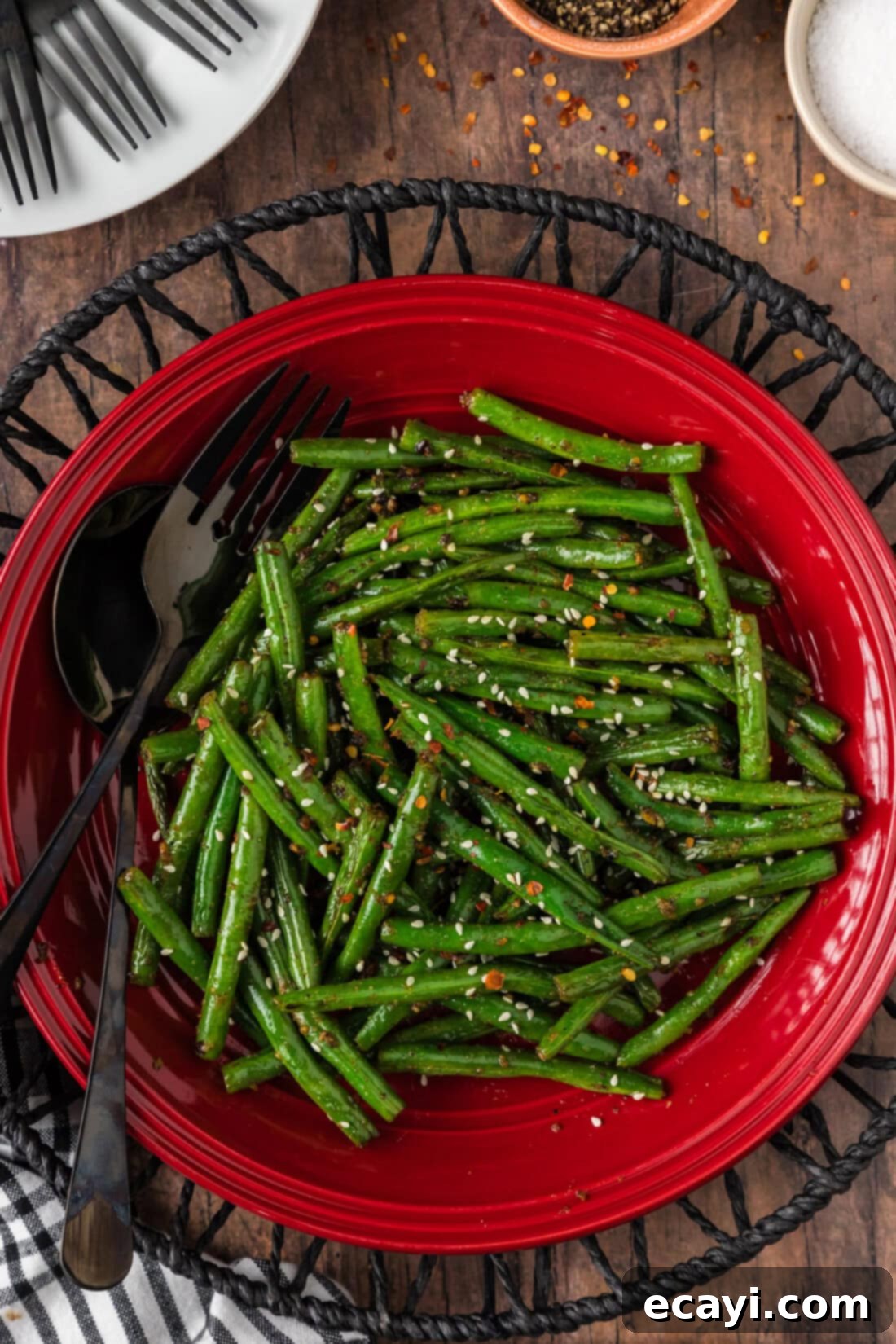 Garlic Sauteed Green Beans 2 Sautéed Green Beans on a red plate with a serving fork and spoon resting to the side