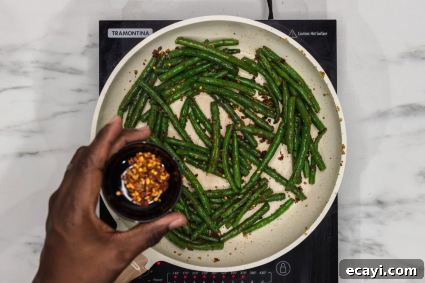 Garlic Sauteed Green Beans 8 hand holding red pepper flakes over sauteed green beans
