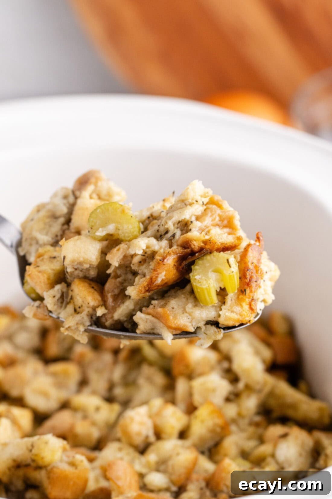 Easy Crockpot Stuffing 2 Close up photo of a spoonful of Crockpot Stuffing, showing golden-brown bread cubes and visible herbs.