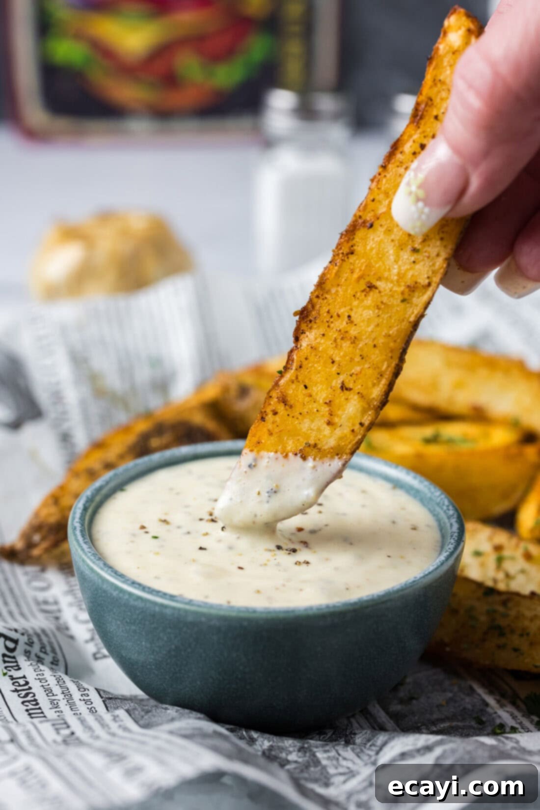 Creamy Garlic Aioli 3 A golden potato wedge being generously dipped into a bowl of homemade Roasted Garlic Aioli, highlighting its creamy texture.