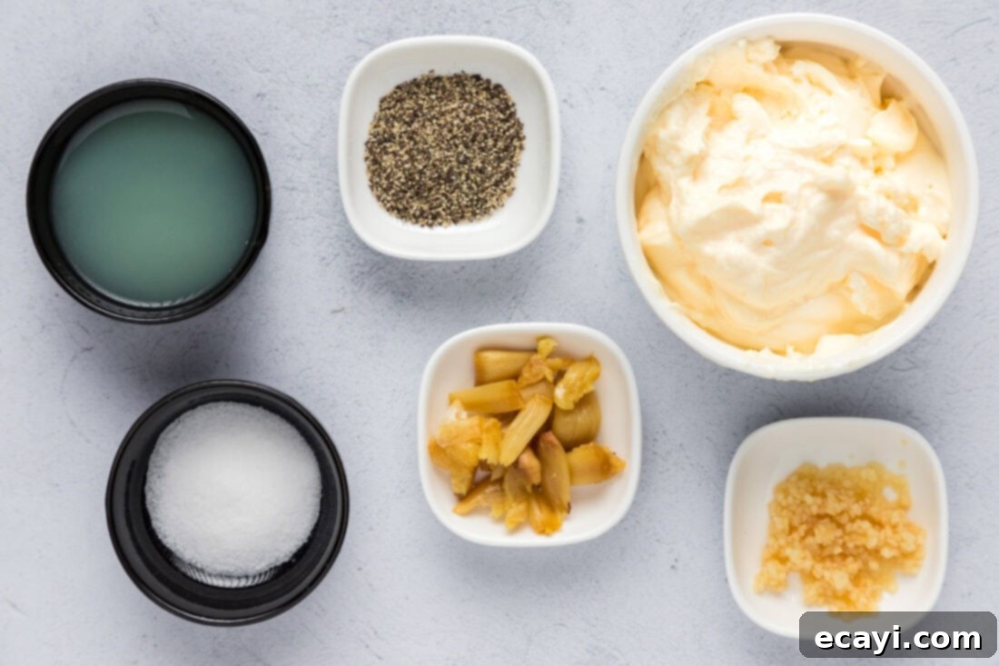 Creamy Garlic Aioli 4 All the fresh ingredients laid out for making creamy Roasted Garlic Aioli, including a head of roasted garlic, lemon, fresh garlic, and mayonnaise.