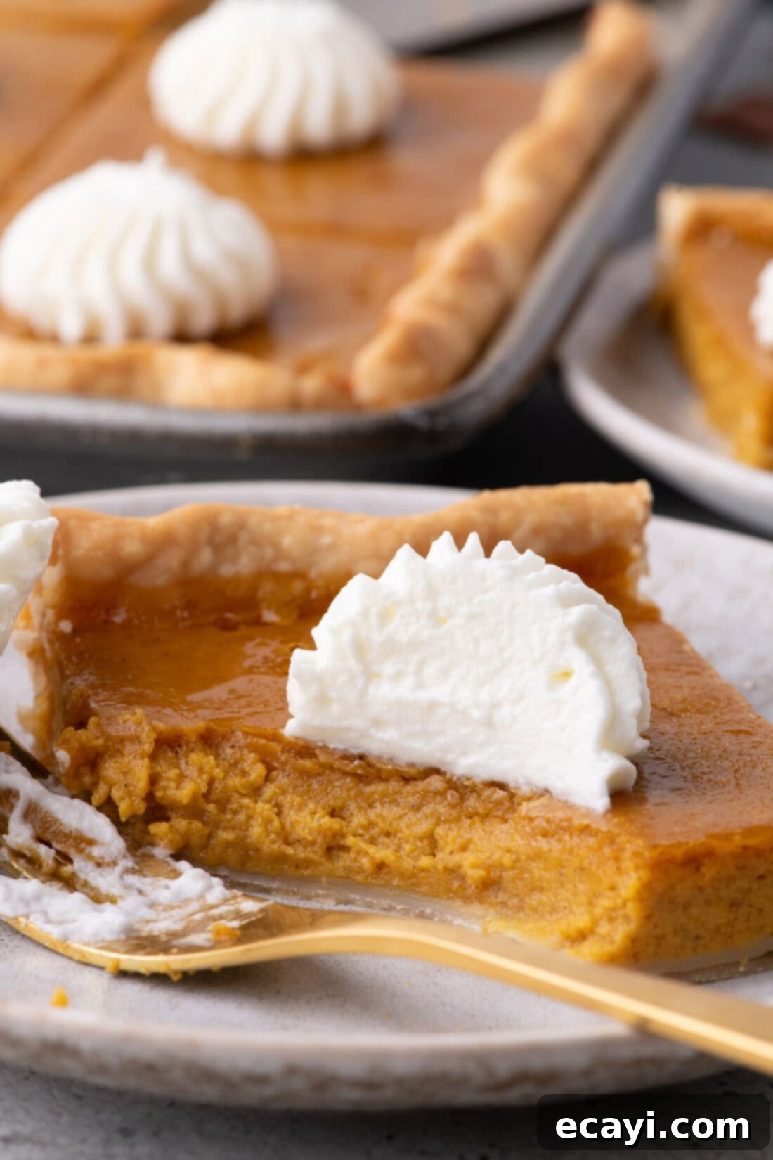 Family Sized Sheet Pan Pumpkin Pie 19 A slice of pumpkin slab pie with a bite taken out, showing the creamy filling and flaky crust