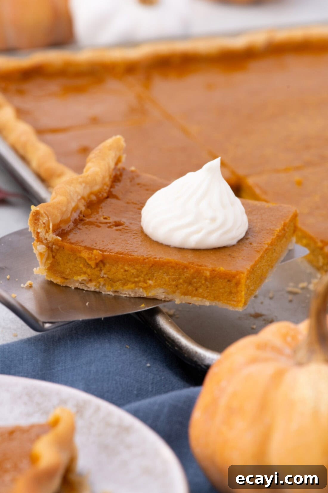 Family Sized Sheet Pan Pumpkin Pie 3 A slice of pumpkin slab pie being lifted from the pan with a spatula