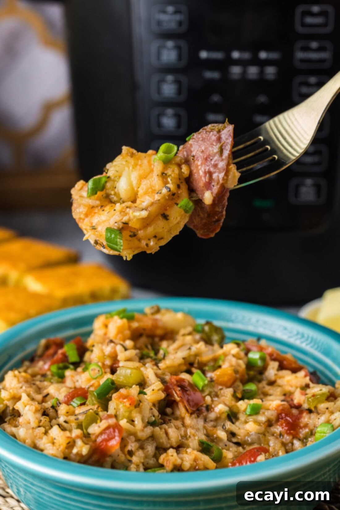 Easy Instant Pot Jambalaya 2 Piece of shrimp and sausage on a fork held above a bowl of Instant Pot Jambalaya