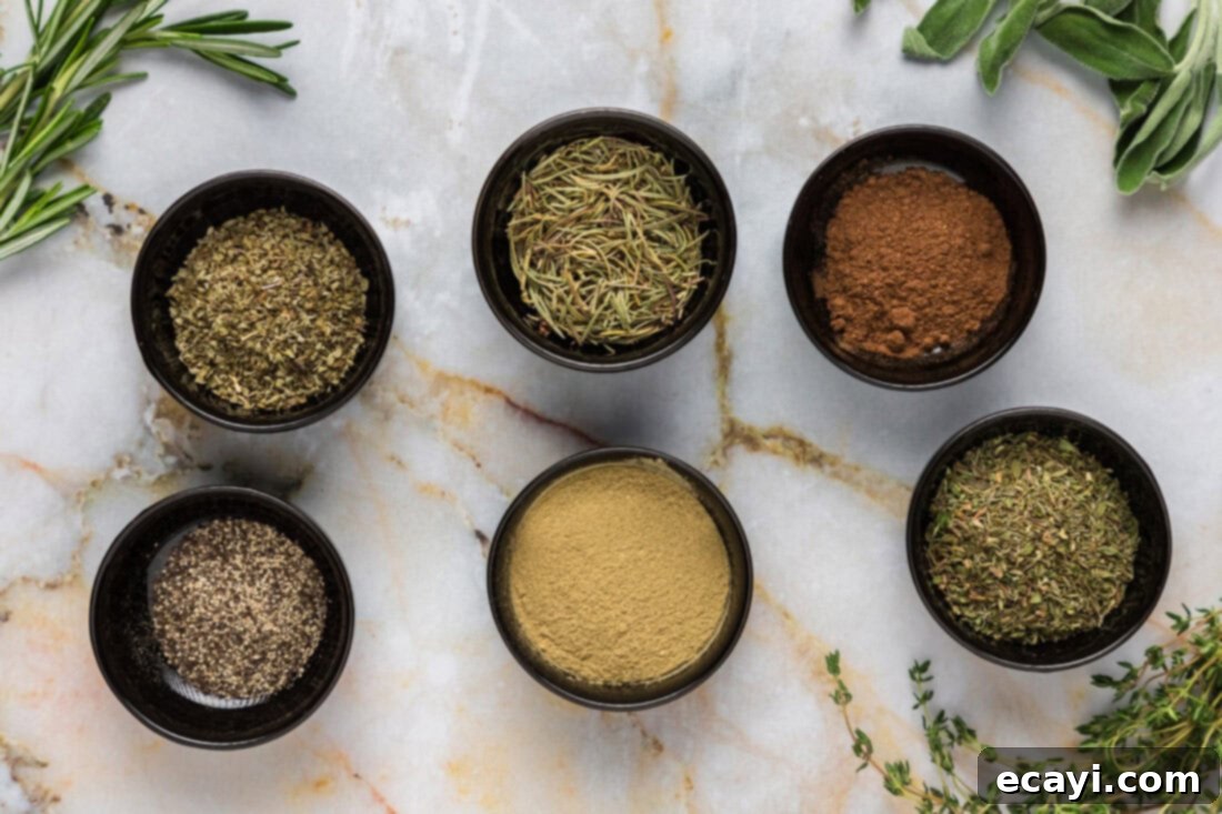 Savory Poultry Blend 4 Variety of dried herbs and spices laid out on a table, including rosemary, marjoram, thyme, sage, nutmeg, and black pepper, ingredients for homemade poultry seasoning