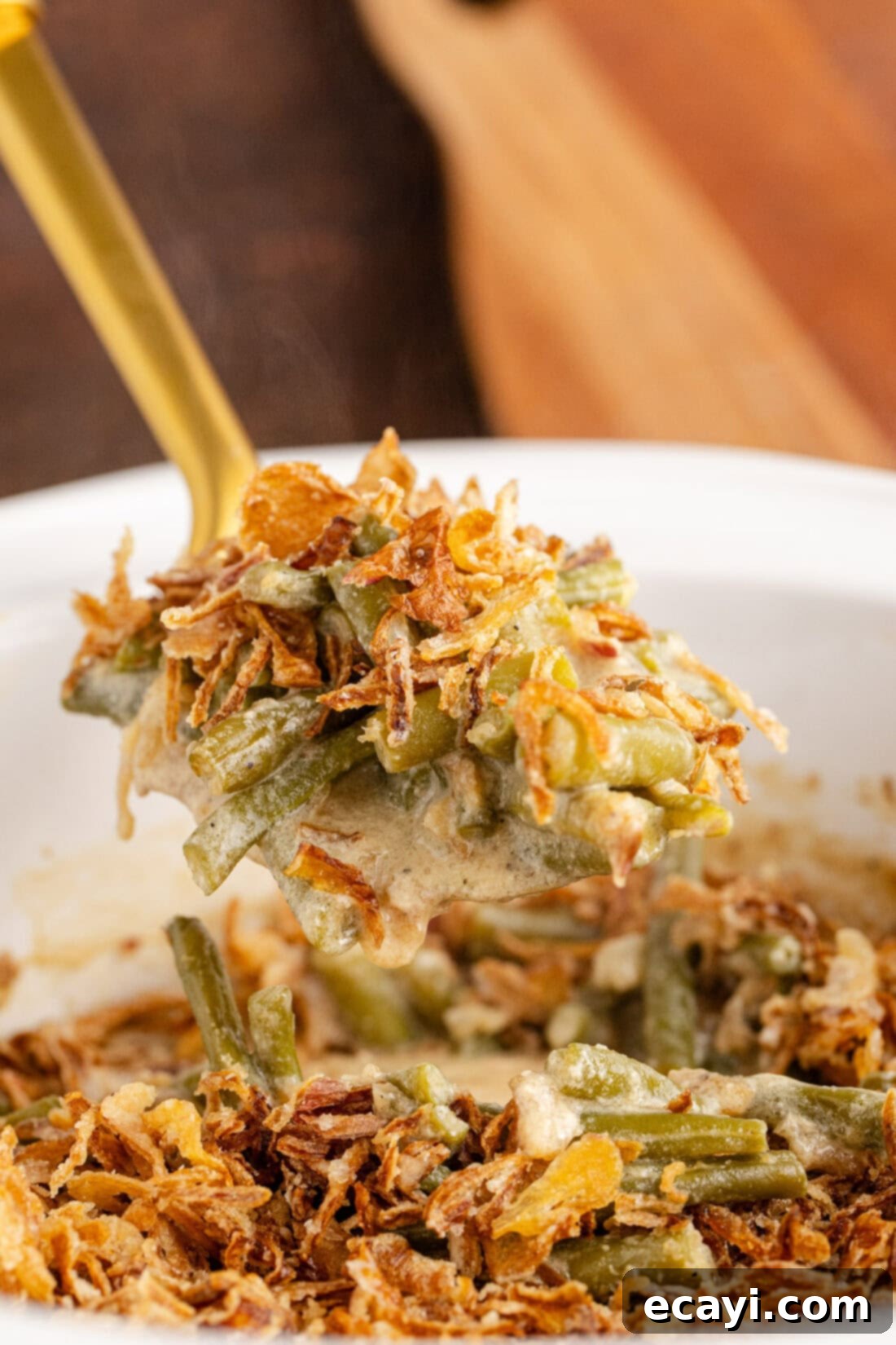 Effortless Crockpot Green Bean Bake 2 Close up photo of a spoonful of Crockpot Green Bean Casserole, showcasing the creamy texture and crispy fried onions.