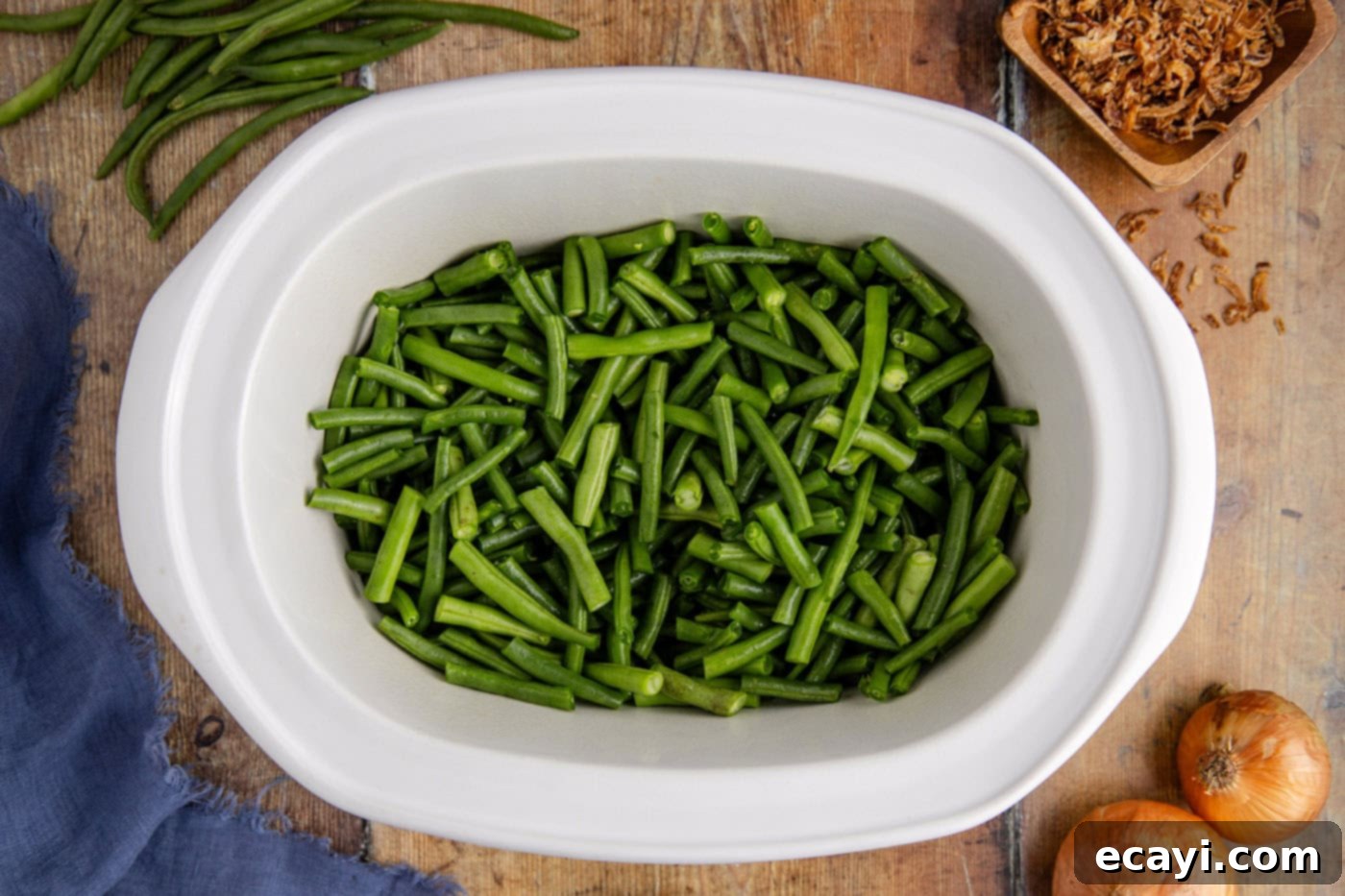 Effortless Crockpot Green Bean Bake 5 trimmed green beans in a slow cooker crock, ready for other ingredients.