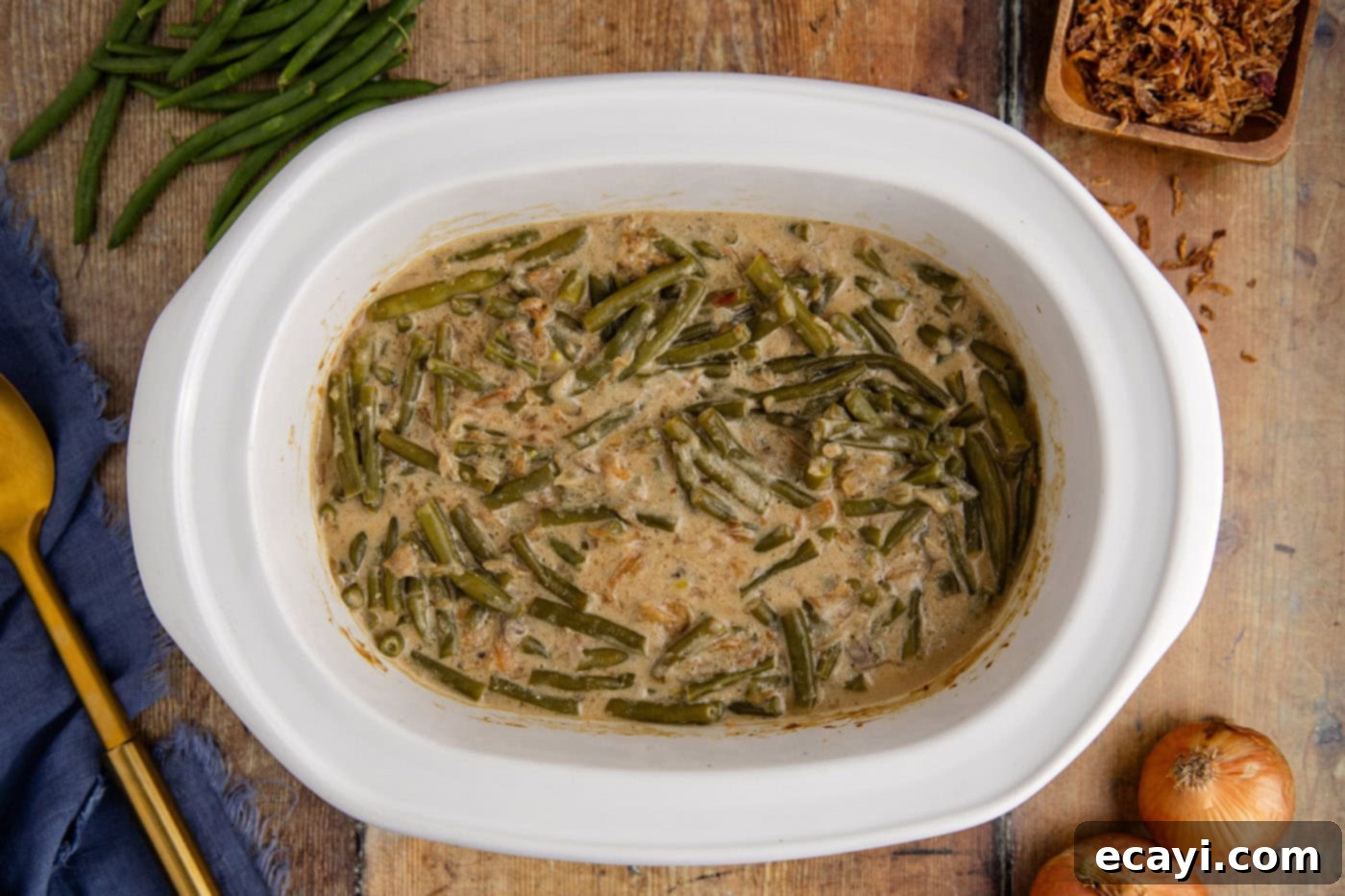 Effortless Crockpot Green Bean Bake 8 cooked green bean casserole in a crockpot, topped with crispy fried onions, ready to be served.
