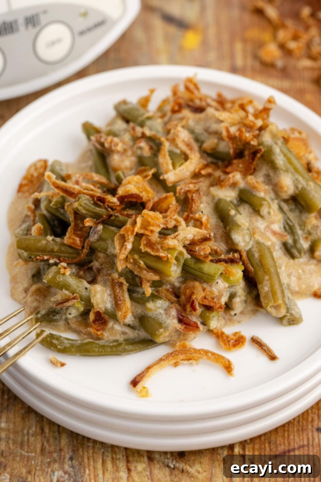 Effortless Crockpot Green Bean Bake 9 Plate of Crockpot Green Bean Casserole with a fork, showing a generous serving with crispy onions.