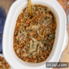Effortless Crockpot Green Bean Bake 10 Overhead photo of Green Bean Casserole in a Crockpot with a spoon in it, garnished with fresh herbs.
