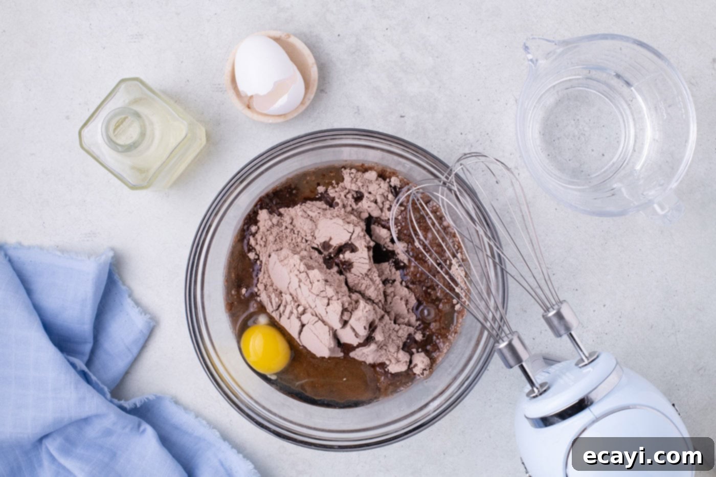 Decadent Pecan Pie Brownies 5 cake mix with oil and eggs in a bowl with a whisk, showing the initial steps of preparing the brownie batter