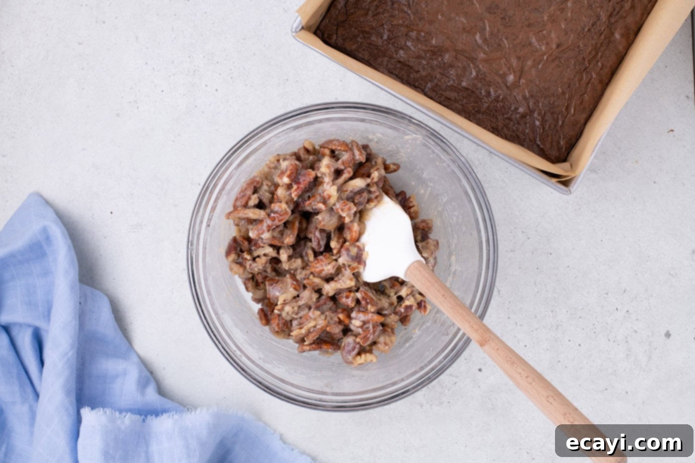 Decadent Pecan Pie Brownies 7 pecan pie topping ingredients mixed in a bowl with a rubber spatula, creating a sweet and nutty mixture