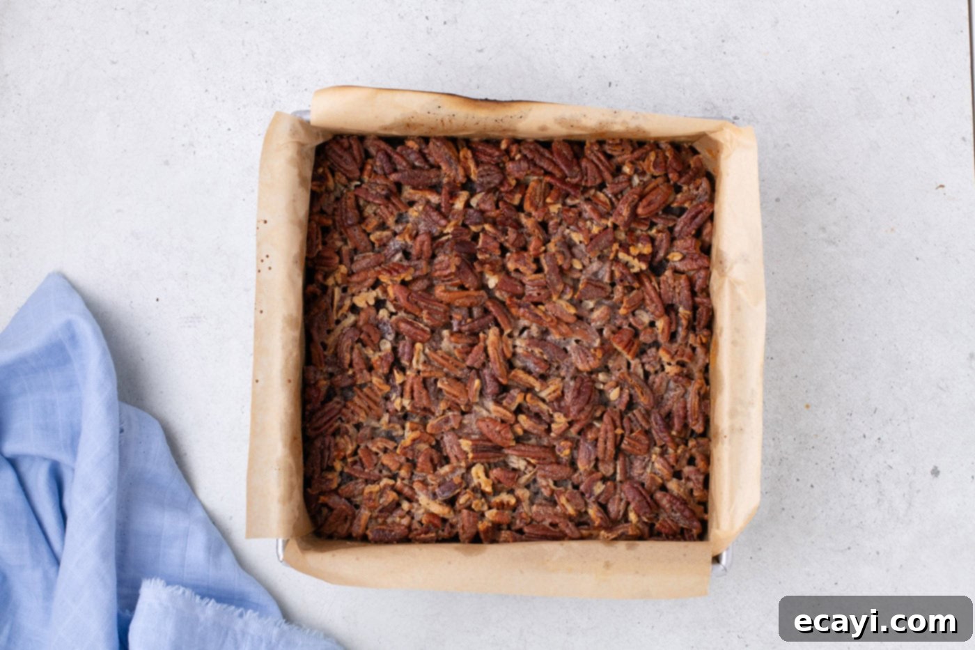 Decadent Pecan Pie Brownies 9 baked pecan pie brownies fresh out of the oven in a baking pan, with a golden brown and bubbly topping