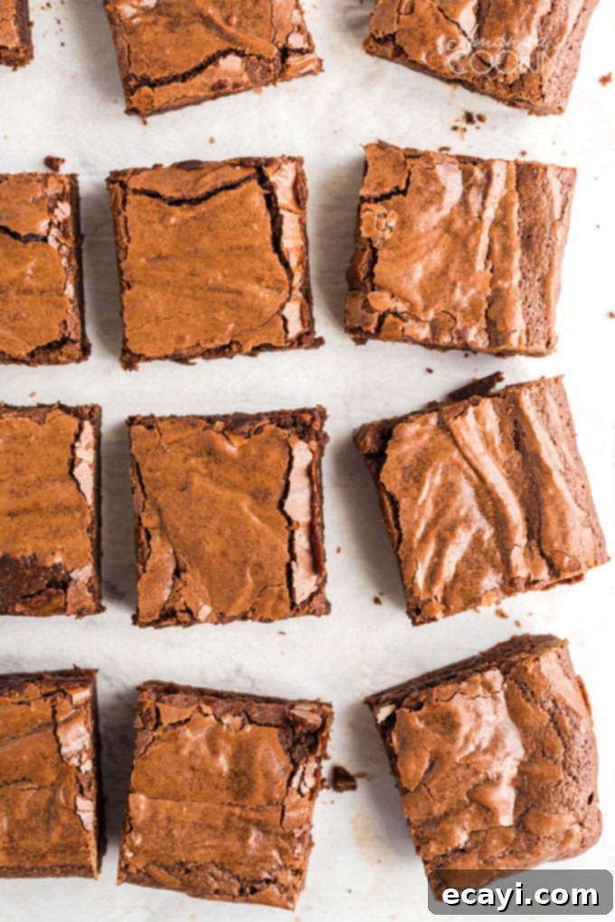 Easy 7-ingredient recipe for chewy fudge brownies Overhead shot of perfectly cut fudgy brownies on a parchment-lined baking sheet