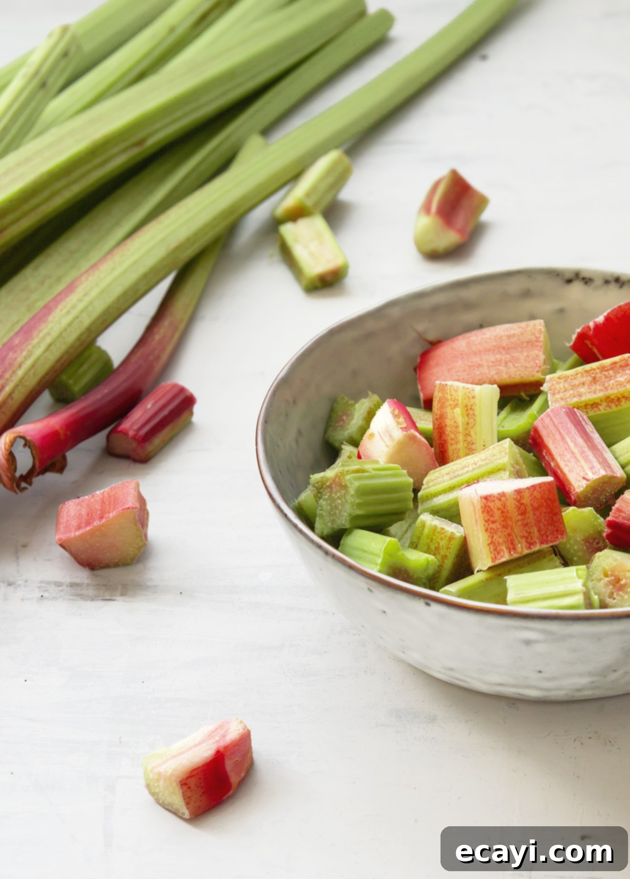 Rosé-Kissed Strawberry Rhubarb Compote 3 Freshly chopped red and green rhubarb stalks on a cutting board, ready for making compote.