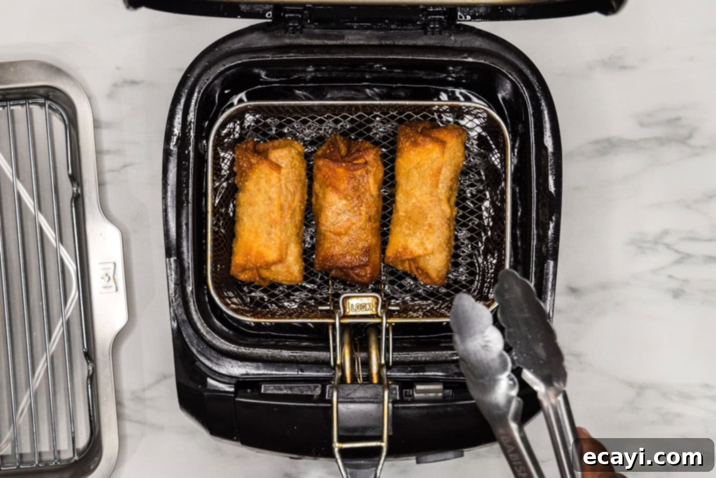 Prawn Spring Rolls 12 tongs grabbing deep fried egg roll from basket