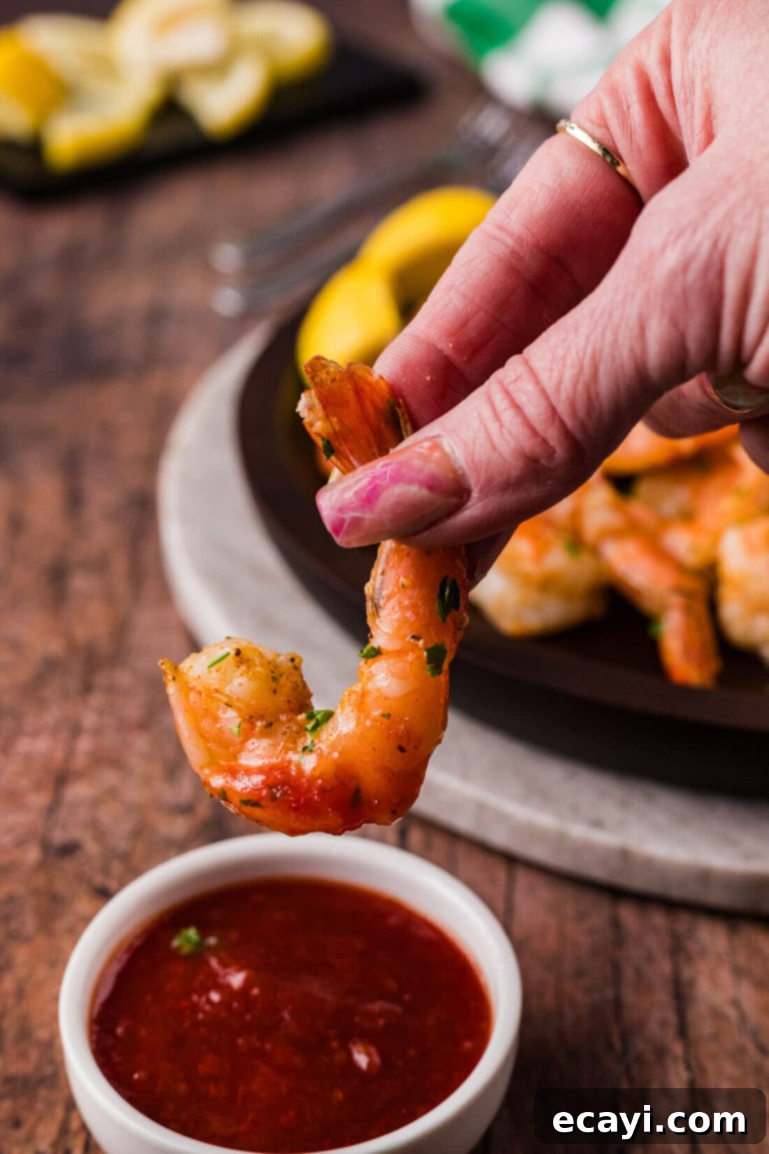 Tender Steamed Shrimp 8 Hand holding a Steamed Shrimp above a bowl of cocktail sauce