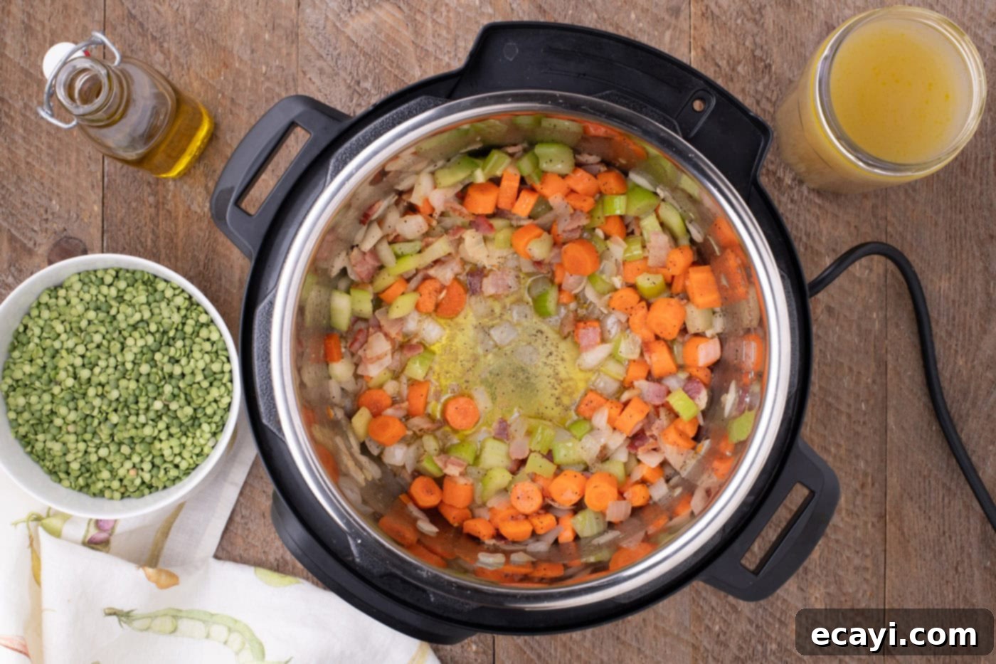 Hearty Instant Pot Split Pea Soup 7 Chicken stock being poured into the Instant Pot over sautéed vegetables, preparing for the split peas.