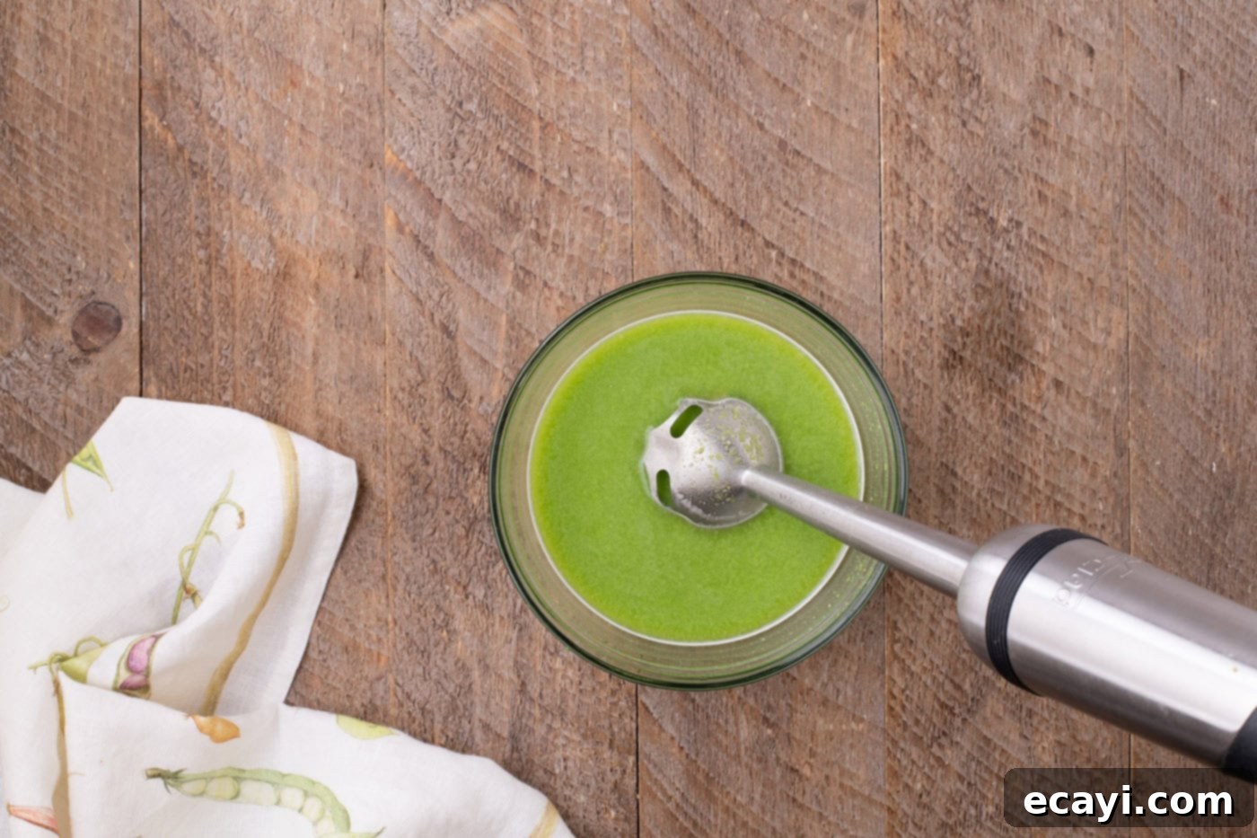 Hearty Instant Pot Split Pea Soup 10 Frozen peas and reserved chicken stock being blended with an immersion blender in a bowl to create a smooth puree.