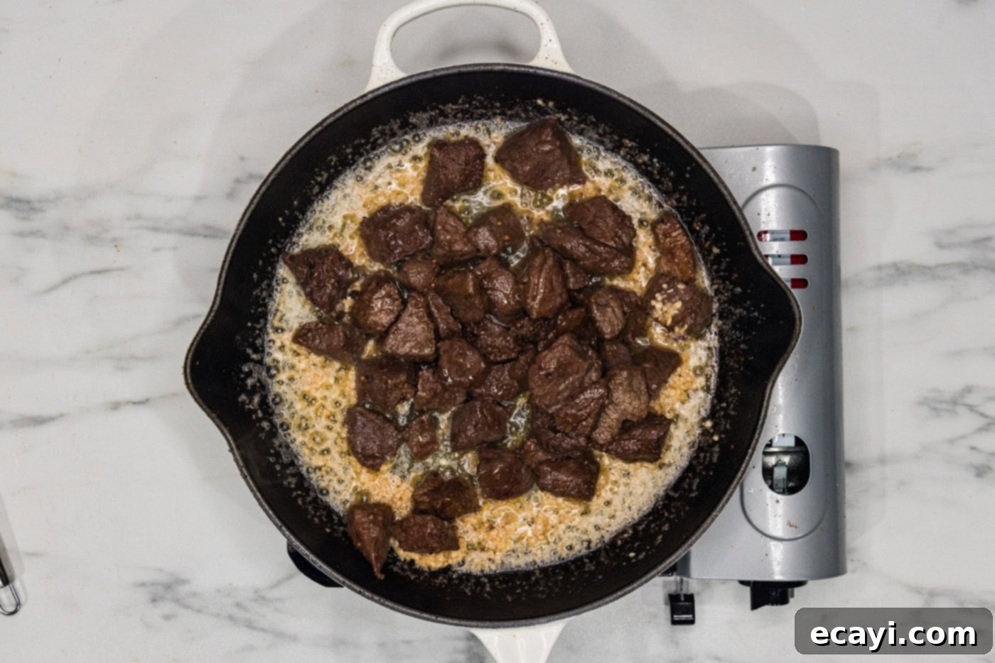 Mouthwatering Garlic Butter Steak Bites 8 Steak bites in a skillet with the garlic butter sauce, showing them being tossed to coat each piece.