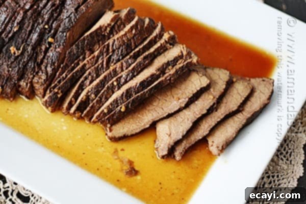 Velvet Brandy Pot Roast 2 A close up overhead of sliced slow cooker roast with brandy sauce on a white platter.