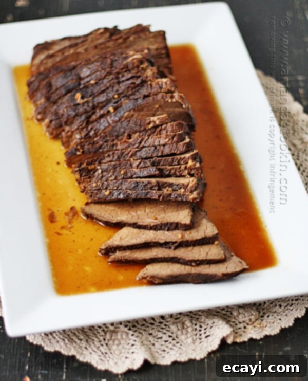 Velvet Brandy Pot Roast 3 An overhead photo of sliced slow cooker roast with brandy sauce on a white platter.