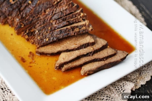 Velvet Brandy Pot Roast 4 A close up of sliced slow cooker roast with brandy sauce on a white platter.