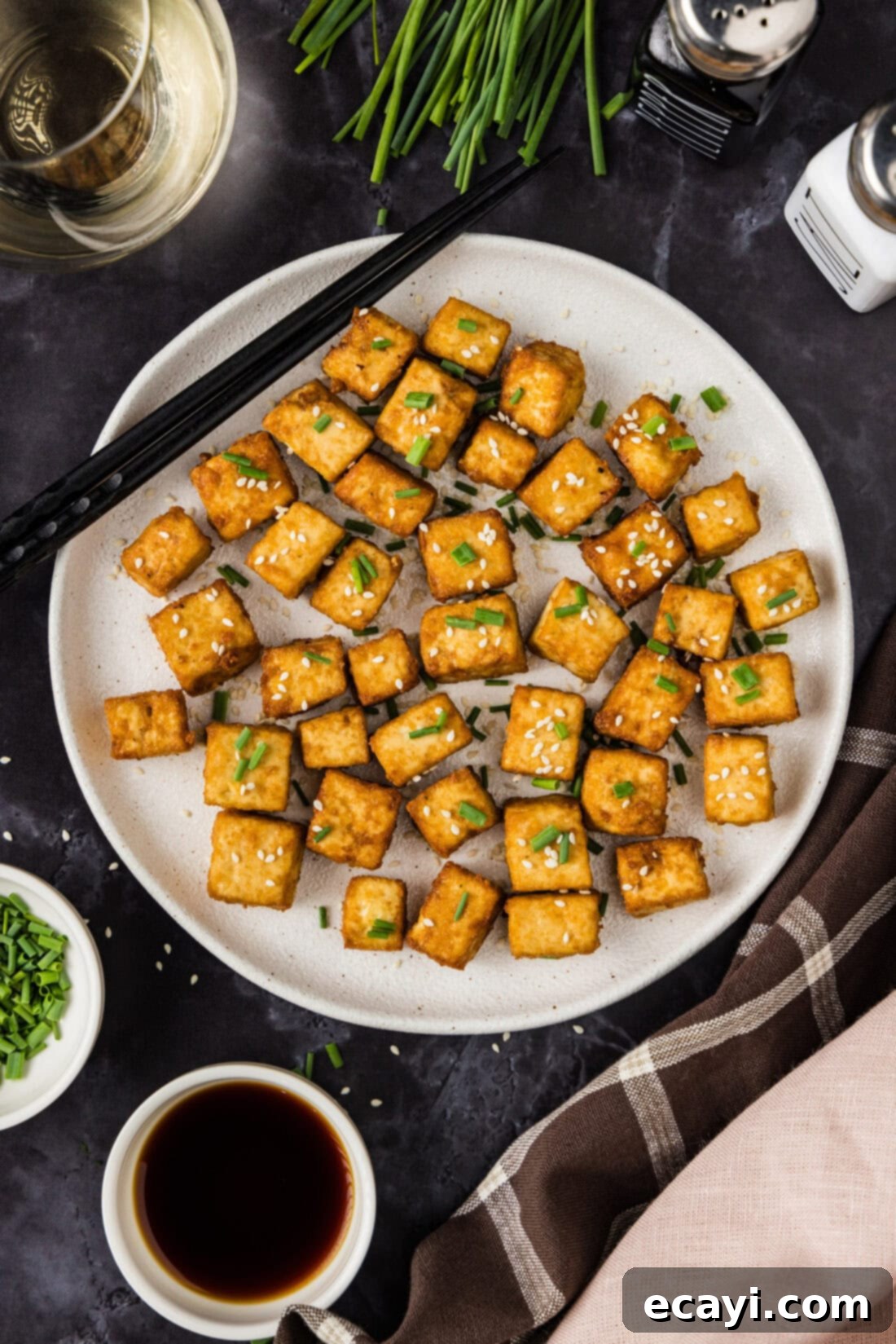 Crispy Golden Tofu 3 A beautifully arranged plate of freshly deep-fried tofu cubes, golden brown and perfectly crispy, accompanied by elegant chopsticks for serving.