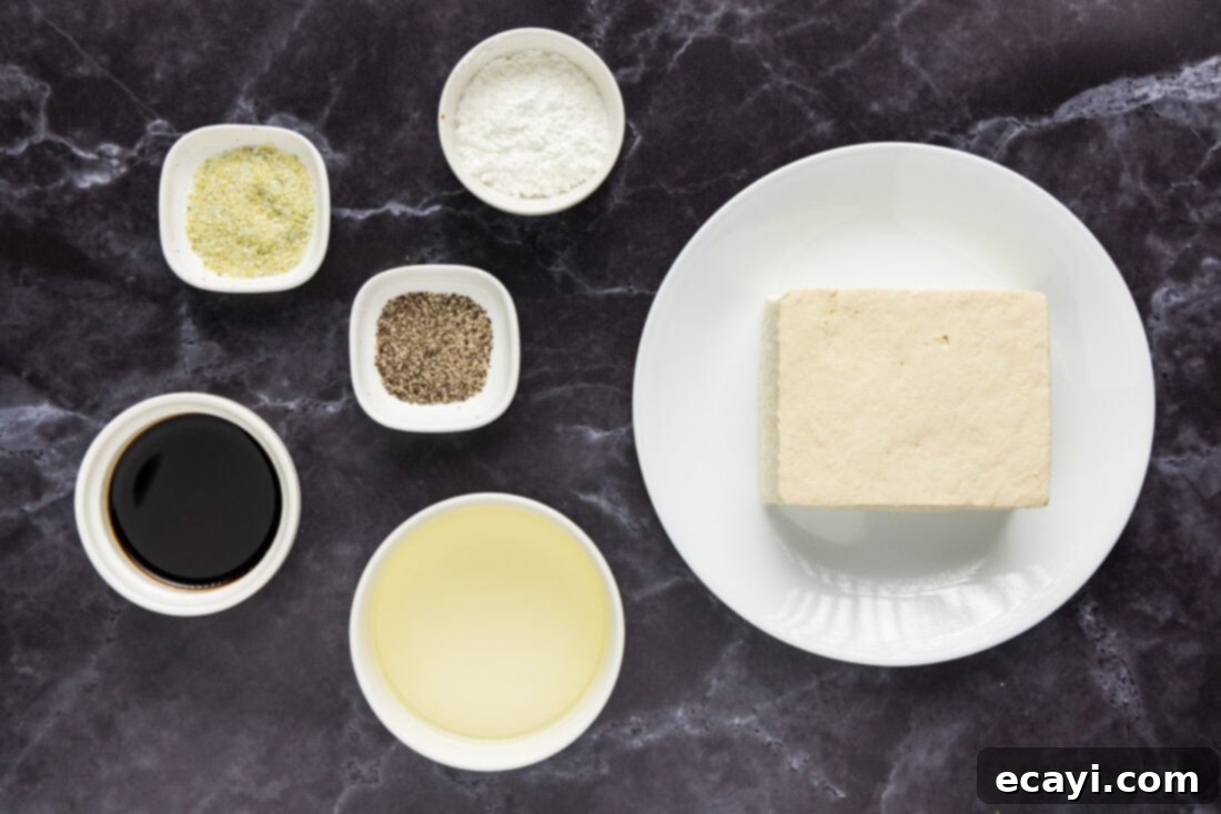 Crispy Golden Tofu 4 A meticulously arranged flat lay of all the fresh ingredients required for making deep-fried tofu, including a block of firm tofu, soy sauce, garlic salt, black pepper, and cornstarch, ready for preparation.