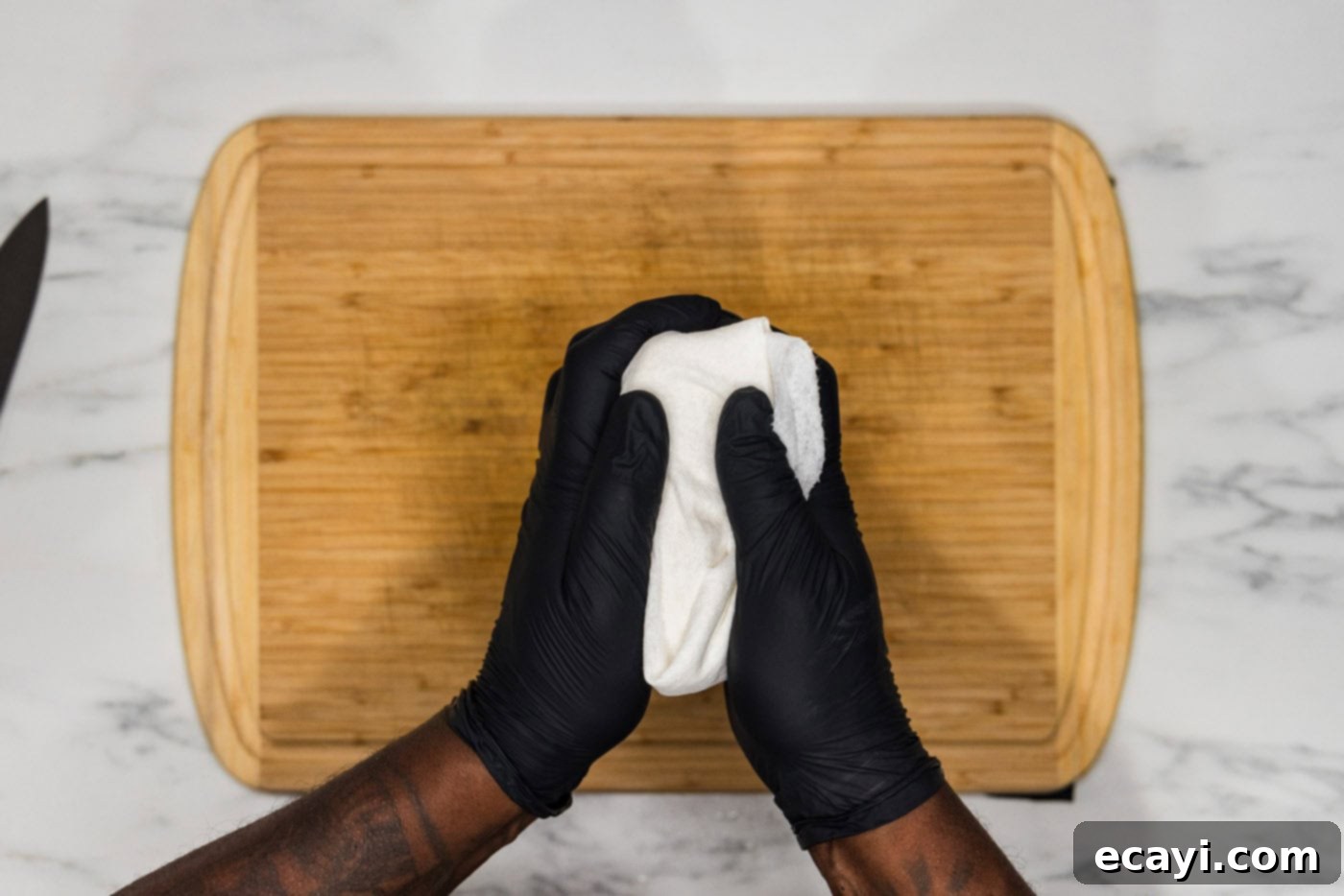 Crispy Golden Tofu 5 Hands demonstrating the essential process of squeezing excess moisture from a block of tofu, meticulously wrapped in layers of absorbent paper towels, prior to cooking.