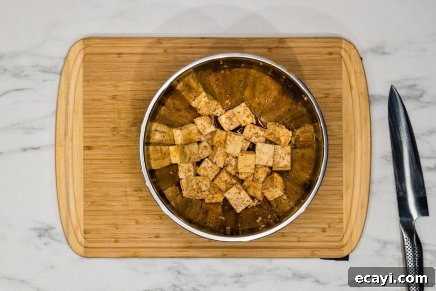 Crispy Golden Tofu 7 Close-up view of seasoned tofu cubes nestled in a mixing bowl, glistening with an even coating of savory soy sauce, aromatic garlic salt, and freshly ground black pepper.
