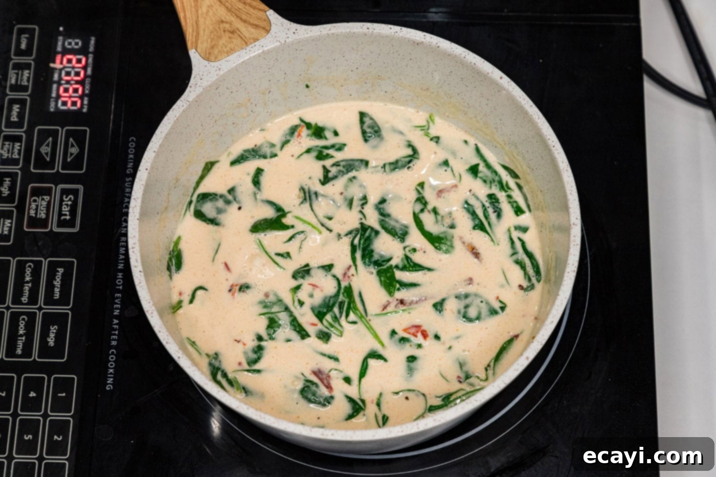 Silken Salmon Perfection 8 spinach added to cream sauce in a skillet with sun dried tomatoes
