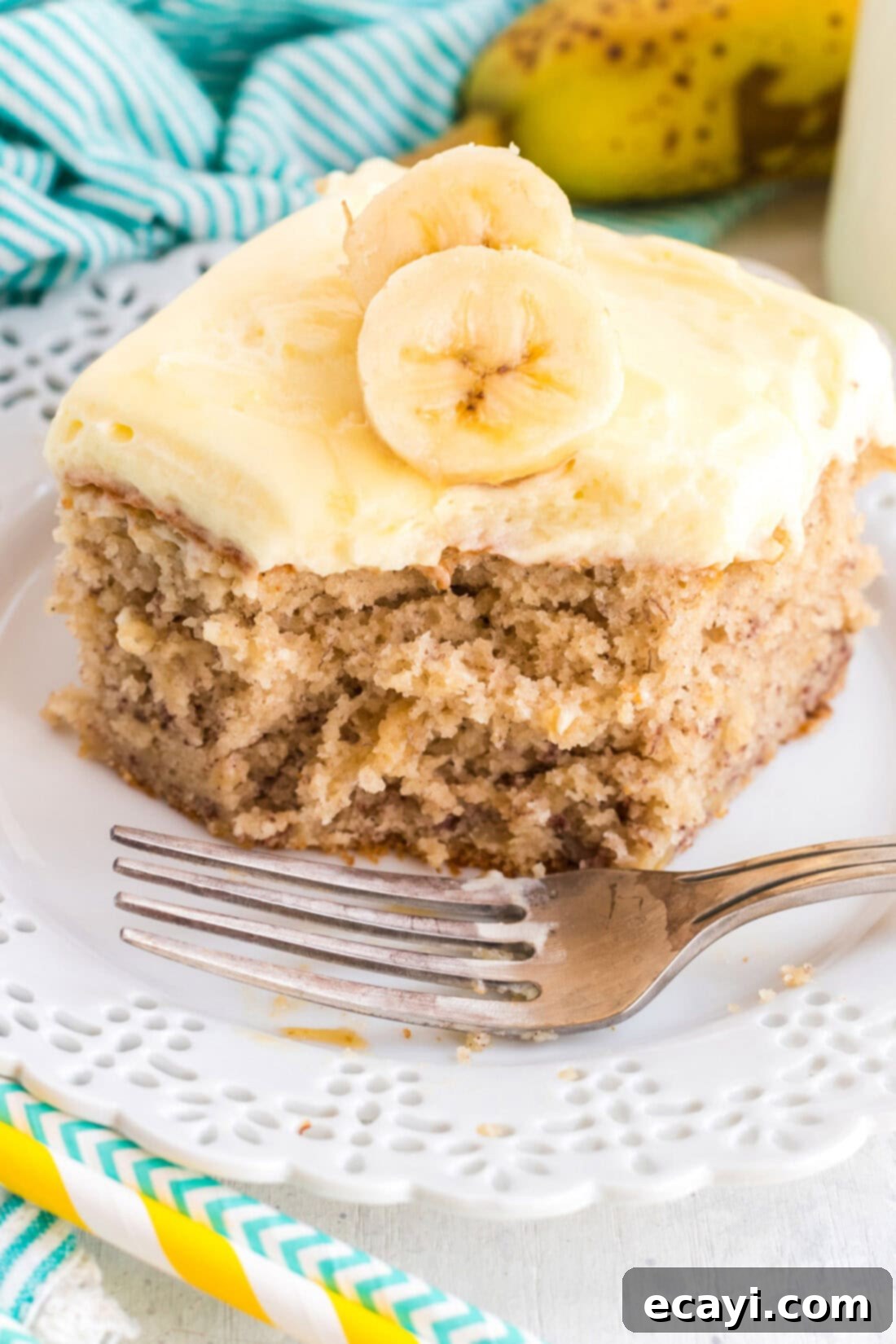 This banana cake using cake mix is positively delicious, easy to make and is topped with an amazing banana flavored whipped cream frosting! slice of banana cake with a bite out of it, topped with banana whipped cream frosting
