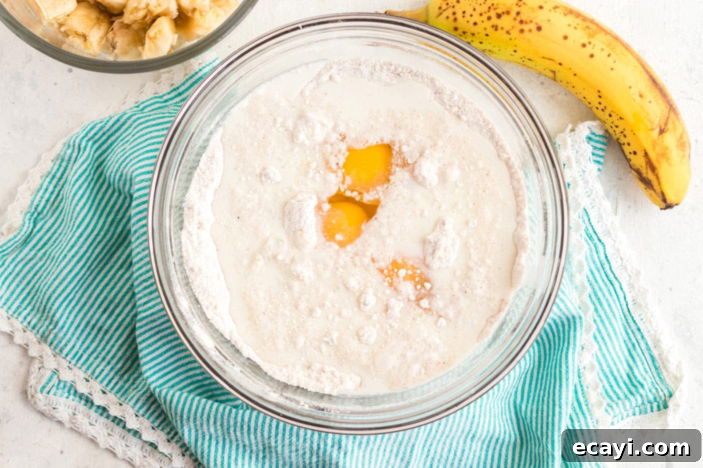 Effortless Banana Cake 4 eggs being added to a bowl of cake mix and other ingredients