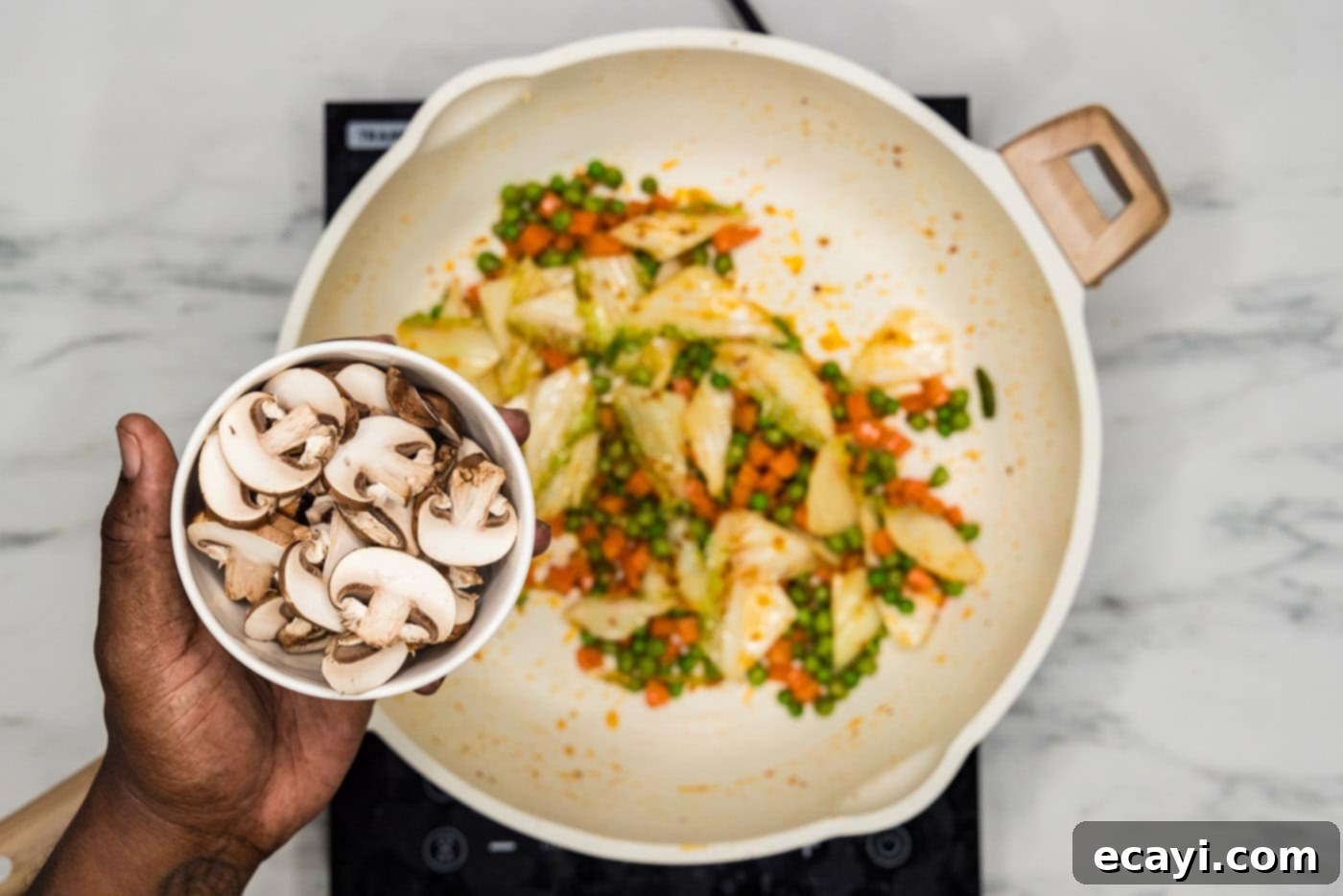 Savory Korean Fried Rice 5 Adding sliced mushrooms to a skillet filled with stir-fried cabbage, carrots, and peas