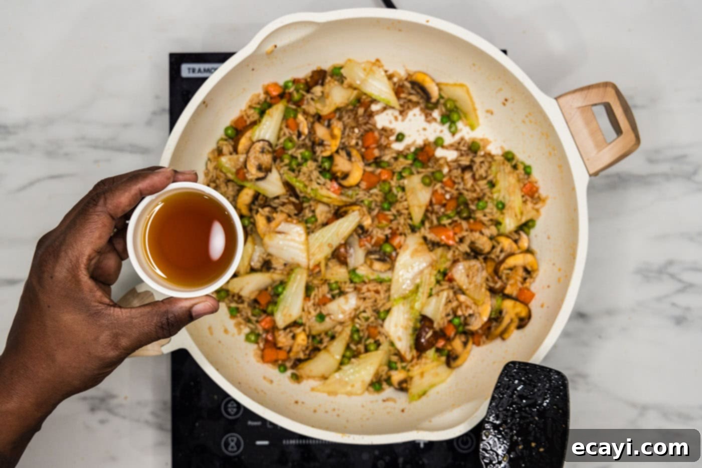 Savory Korean Fried Rice 8 Drizzling sesame oil over a skillet of stir-fried Korean fried rice, enhancing its aroma and flavor