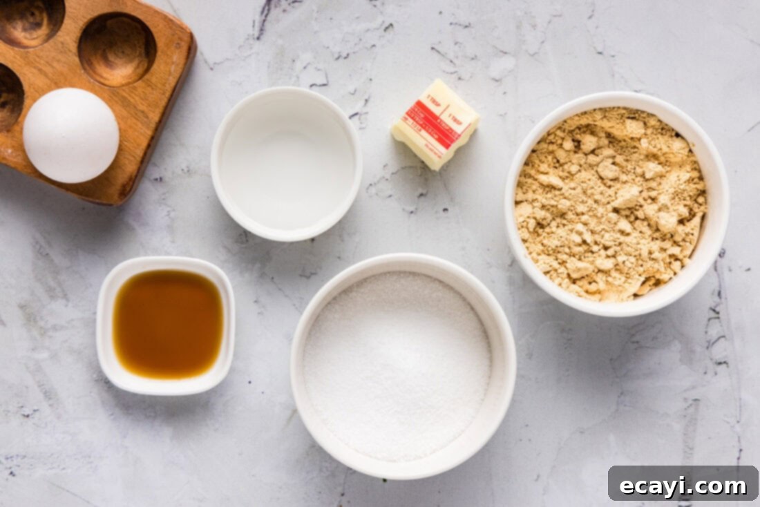 Guilt-Free Keto Peanut Butter Treats 4 Ingredients for Keto Peanut Butter Cookies laid out on a wooden surface, including peanut butter powder, butter, sweetener, egg, vanilla, and water.