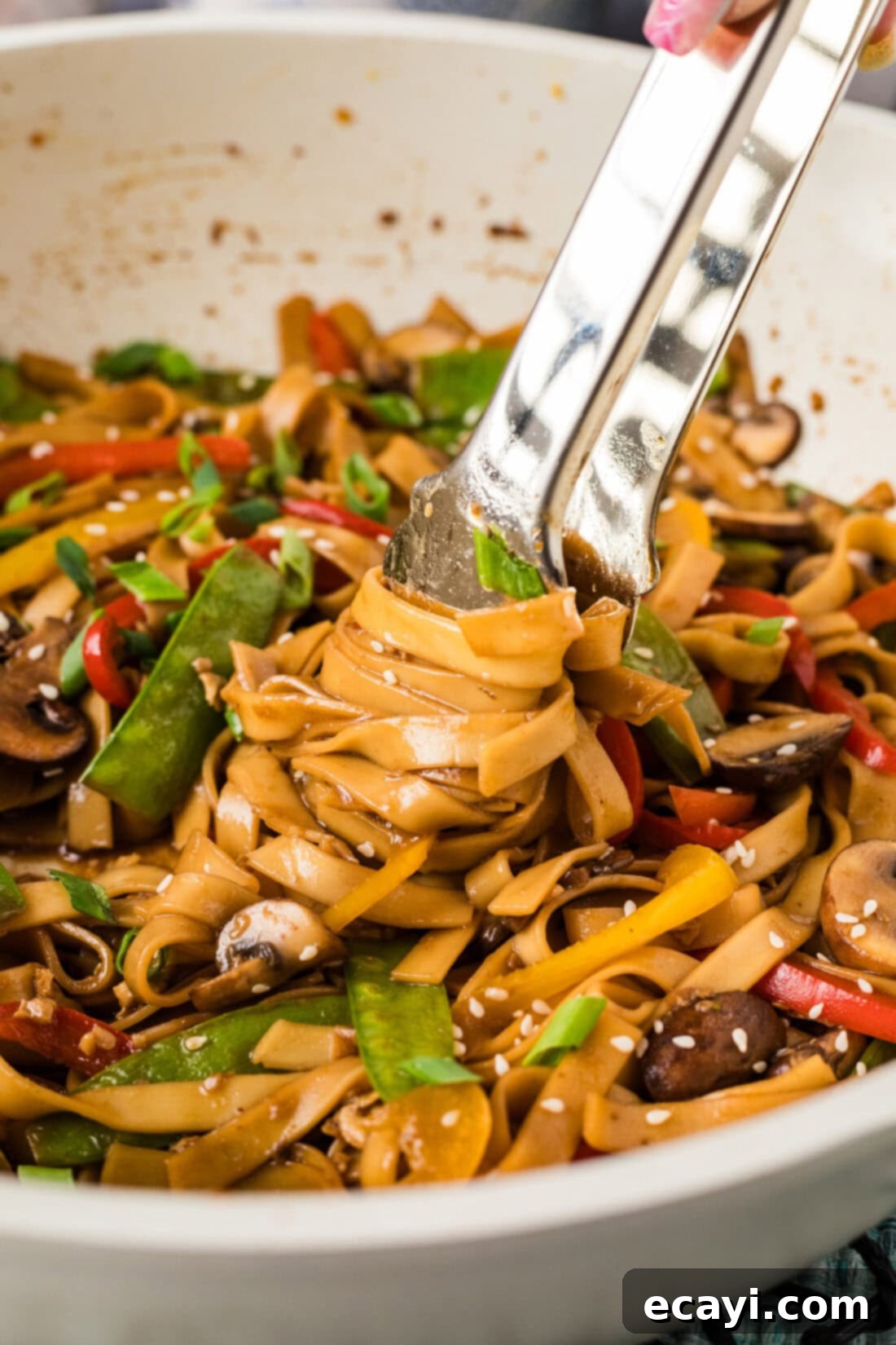 Savory Vegetable Lo Mein 11 Tongs twisting and mixing Vegetable Lo Mein in a skillet, showing the saucy noodles