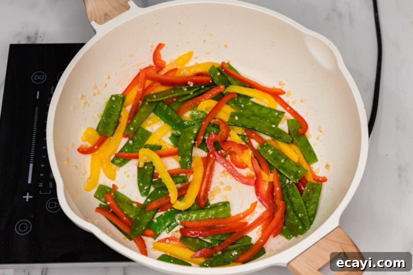 Savory Vegetable Lo Mein 5 Sliced bell peppers and snow peas being stir-fried in a skillet with oil
